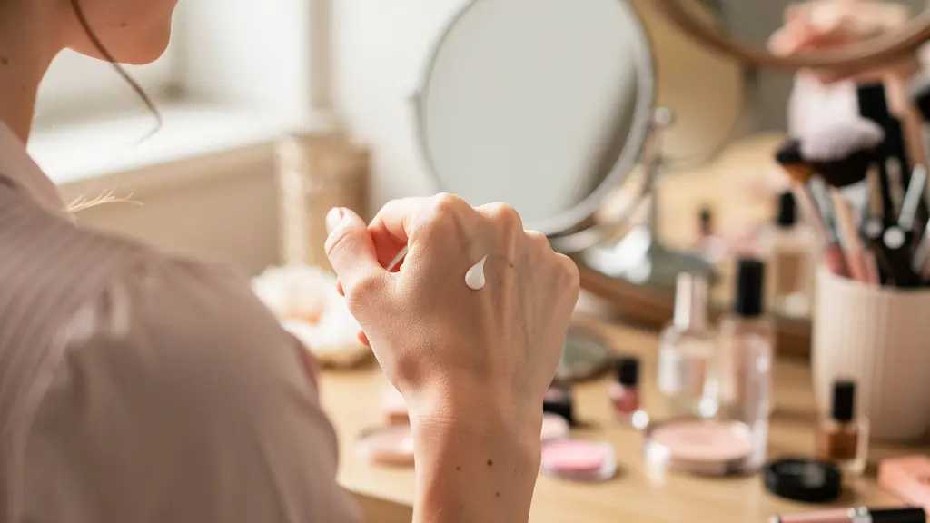 Femme dosant une base de maquillage sur le dos de sa main avant application